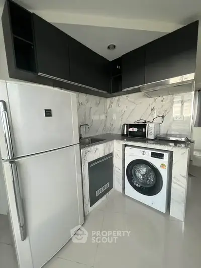 Modern kitchen with sleek appliances and marble backsplash in compact layout.