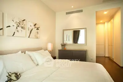 Elegant bedroom with modern decor and soft lighting, featuring a cozy bed and stylish artwork.
