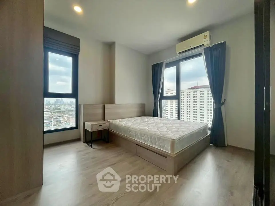 Modern bedroom with large windows and city view, featuring minimalist design and natural light.