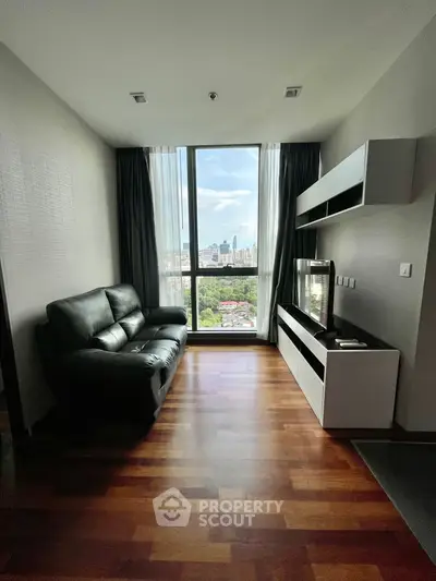 Modern living room with city view, featuring sleek furniture and large window for natural light.