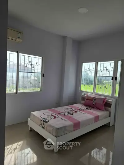 Bright bedroom with single bed and large windows offering scenic views.