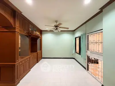Spacious living room with built-in wooden cabinets and ceiling fan, ideal for cozy family gatherings.