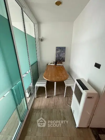 Cozy enclosed balcony with dining table and portable air conditioner, perfect for relaxation.