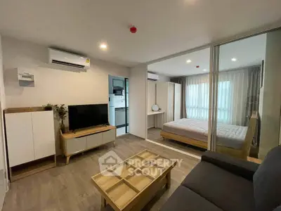 Modern apartment interior with open living room and bedroom, featuring sleek furniture and natural light.