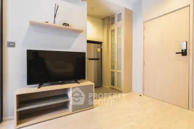 Modern apartment interior with sleek TV setup and compact kitchen area.