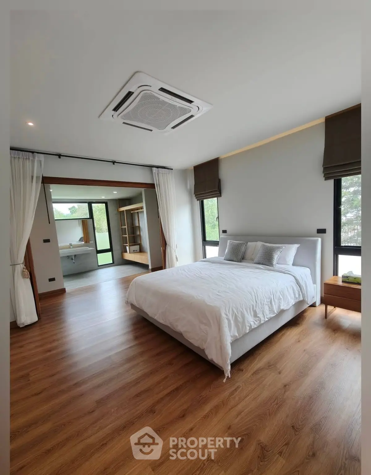 Spacious modern bedroom with wooden flooring and large windows