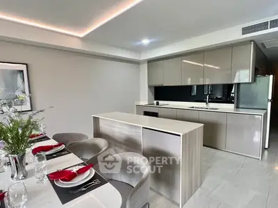 Modern kitchen with sleek cabinetry and dining area, featuring elegant decor and open layout.