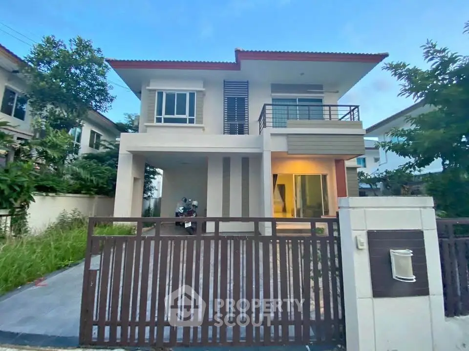 Modern two-story house with gated entrance and balcony in suburban neighborhood.