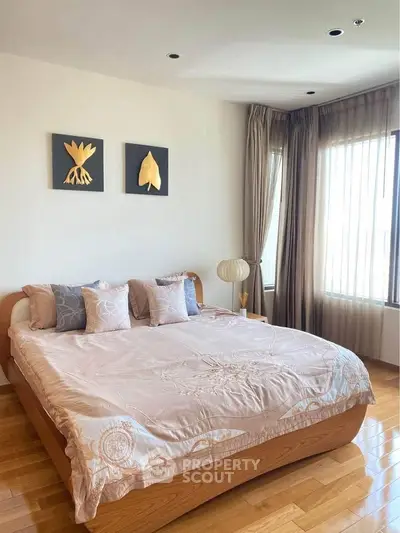 Elegant bedroom with cozy bed and natural light, featuring stylish decor and wooden flooring.