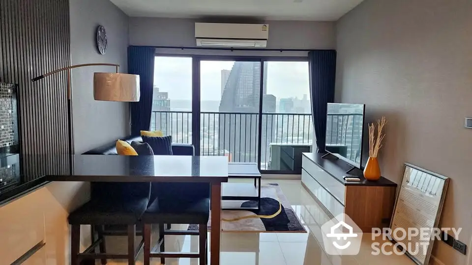 Modern living room with city view, sleek furniture, and large windows in a high-rise apartment.