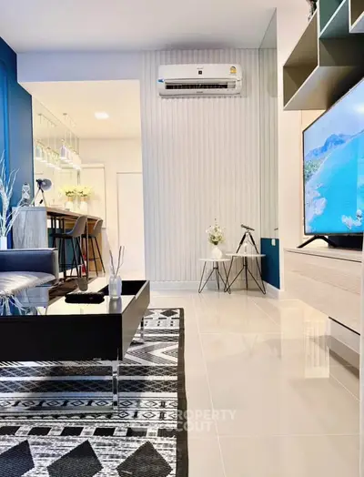 Modern living room with stylish decor and wall-mounted TV, featuring sleek furniture and air conditioning.