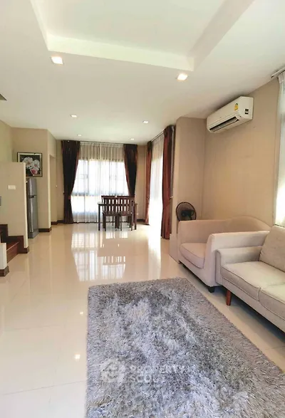 Spacious living room with modern decor and natural light, featuring a cozy sofa and dining area.