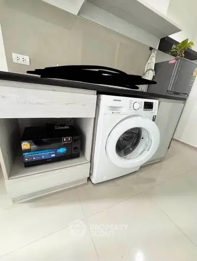 Modern kitchen with washing machine and microwave, sleek cabinetry, and contemporary design.