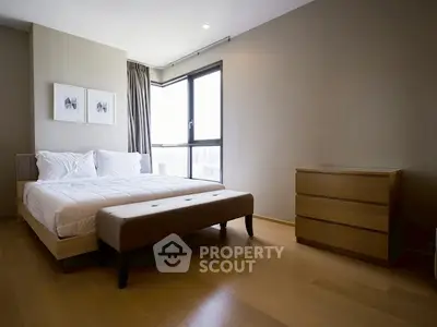 Modern bedroom with minimalist design and large window offering natural light.