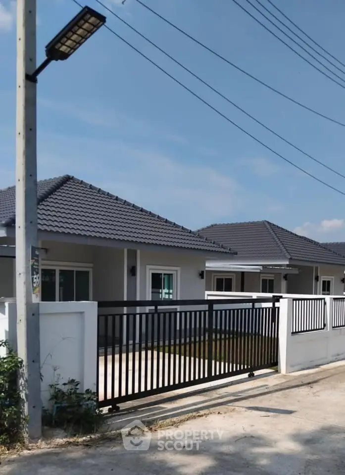 Modern single-story house with tiled roof and gated driveway in a serene neighborhood.