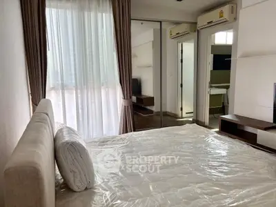 Bright bedroom with large window and modern furnishings in a stylish apartment.