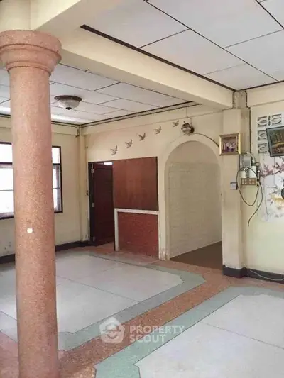 Spacious interior with unique column design and archway, ideal for creative renovation.