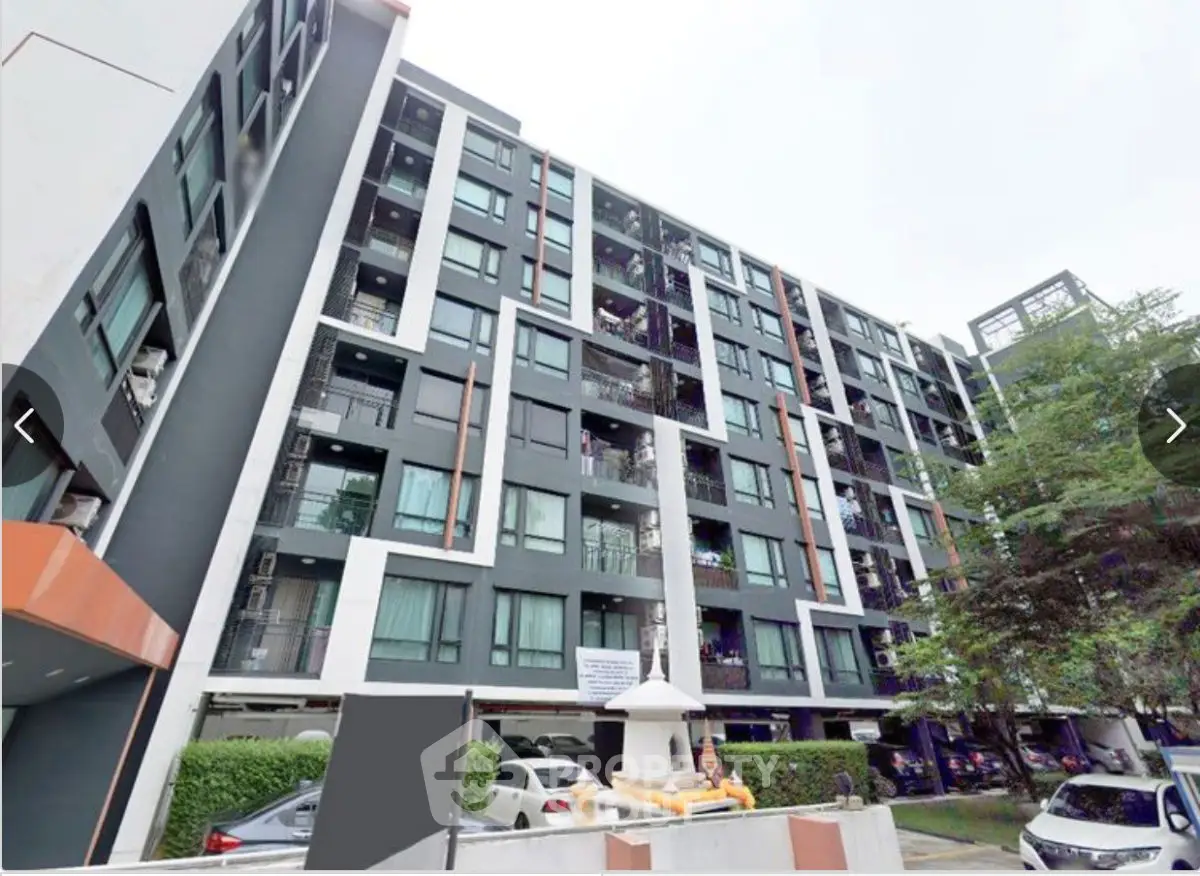 Modern multi-story apartment building with sleek design and ample parking space.