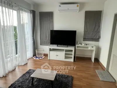 Modern living room with large TV, air conditioning, and balcony access in a stylish apartment.