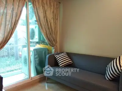 Cozy living room with modern sofa and garden view through sliding glass door.