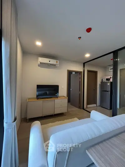 Modern living room with sleek design and air conditioning, featuring a TV and stylish furniture.
