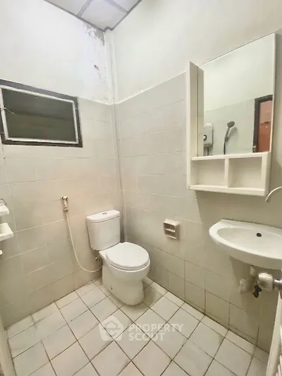 Compact bathroom with white tiles and essential fixtures in a real estate property.