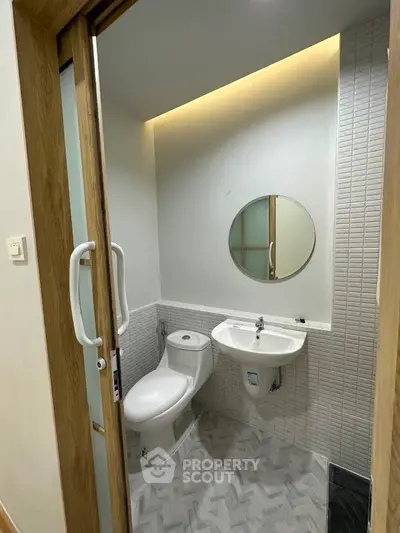 Modern compact bathroom with round mirror and sleek design