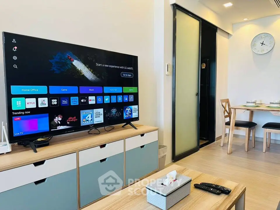 Modern living room with smart TV and dining area, featuring sleek furniture and stylish decor.