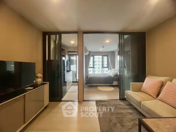 Modern living room with glass doors leading to a cozy bedroom in a stylish apartment.