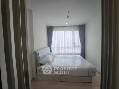 Modern bedroom with large window and elegant curtains, featuring a comfortable bed and minimalist decor.