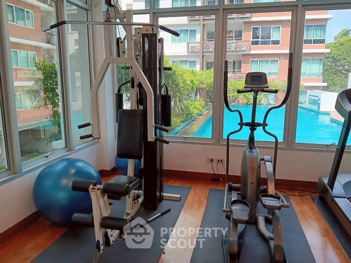Modern gym with exercise equipment and pool view in luxury apartment complex