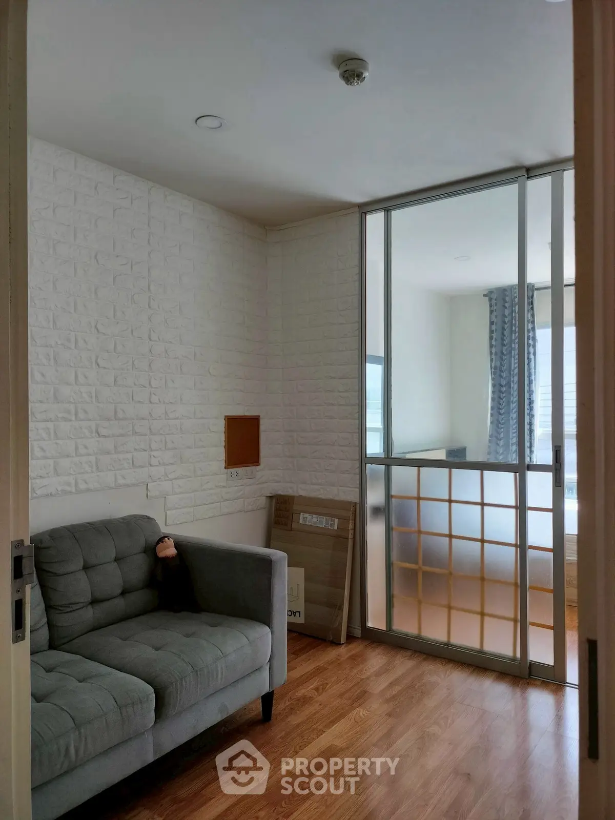 Cozy living room with modern sliding glass partition and stylish gray sofa