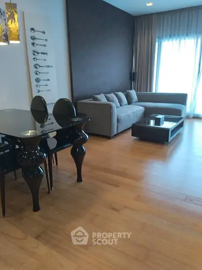 Modern living room with sleek furniture and wooden flooring, featuring a stylish dining area.