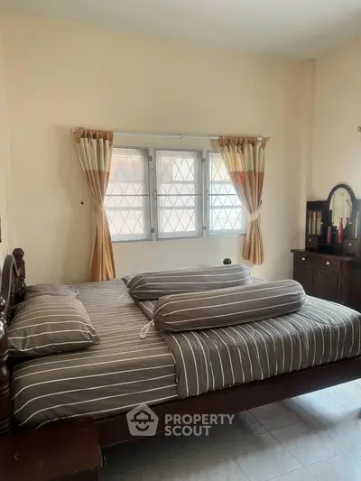 Cozy bedroom with striped bedding and elegant wooden furniture, perfect for relaxation.