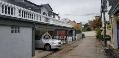 Charming residential street with carport and elegant balcony railing.