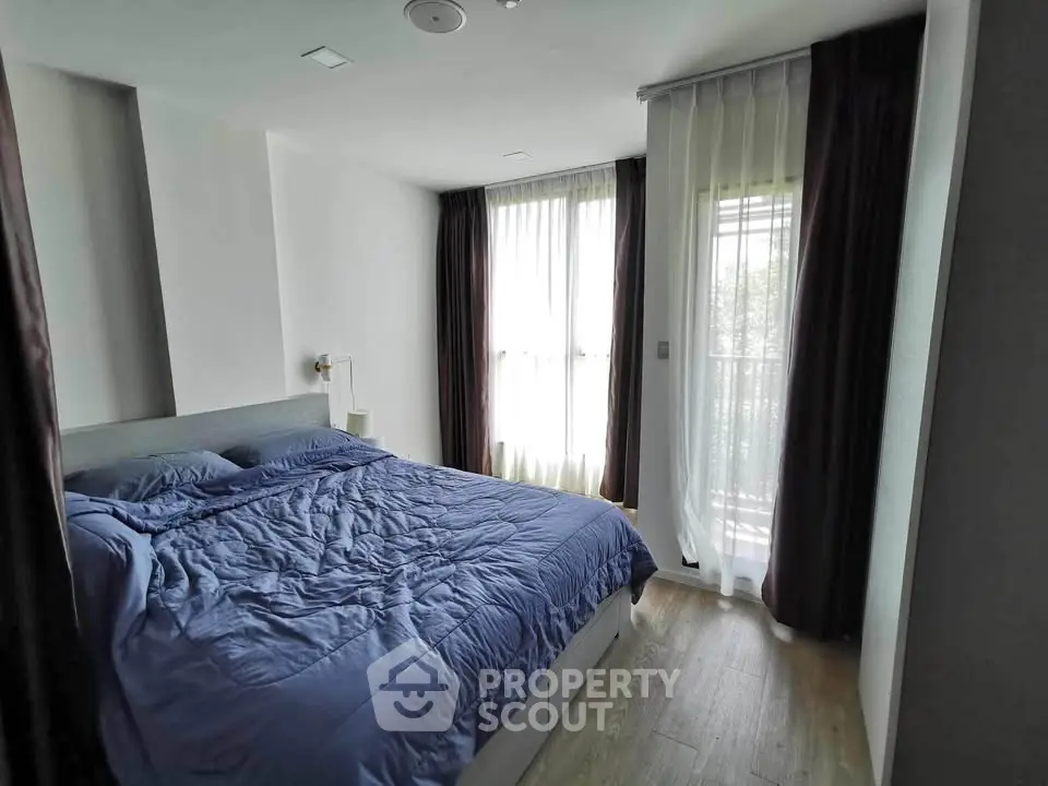 Cozy bedroom with large windows and modern decor, featuring a comfortable bed and elegant curtains.