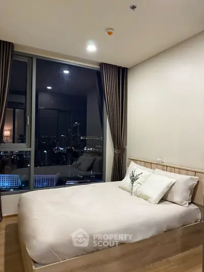 Modern bedroom with city view, cozy bed, and elegant curtains in high-rise apartment.