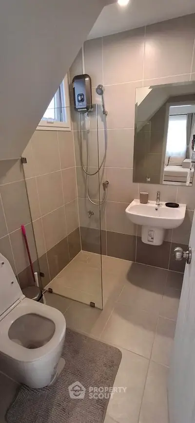 Modern bathroom with glass shower and sleek fixtures in contemporary home.