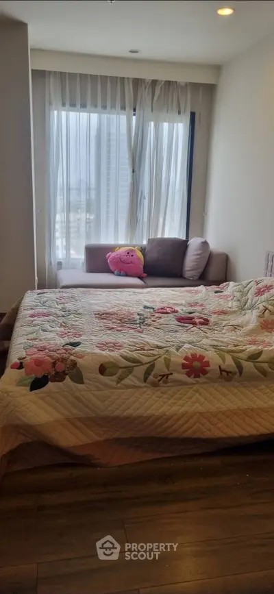 Cozy bedroom with floral bedding and city view from window, perfect for relaxation.