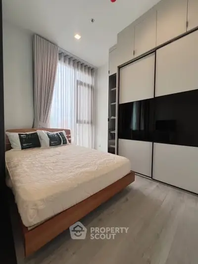 Modern bedroom with sleek wardrobe and large window for natural light.