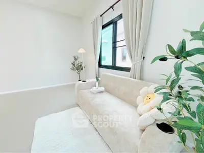 Bright and airy living room with cozy sofa and large window, perfect for relaxation.