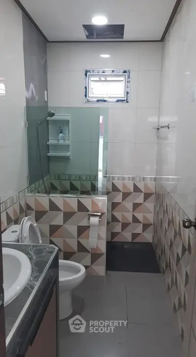 Modern bathroom with geometric tile design and glass shower enclosure