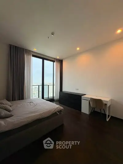 Modern bedroom with city view, featuring sleek furniture and large windows for natural light.