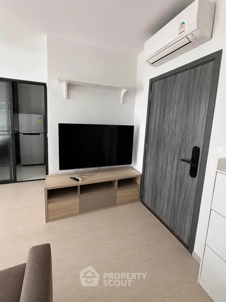 Modern living room with sleek TV setup and air conditioning in a stylish apartment.