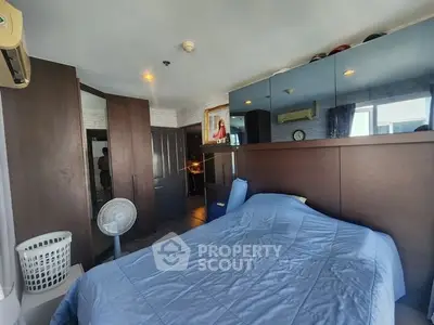 Cozy bedroom with blue bedding, mirrored wardrobe, and air conditioning in modern apartment.
