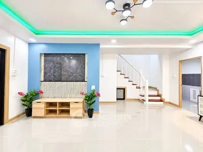Modern living room with stylish decor and staircase in a bright, open space.