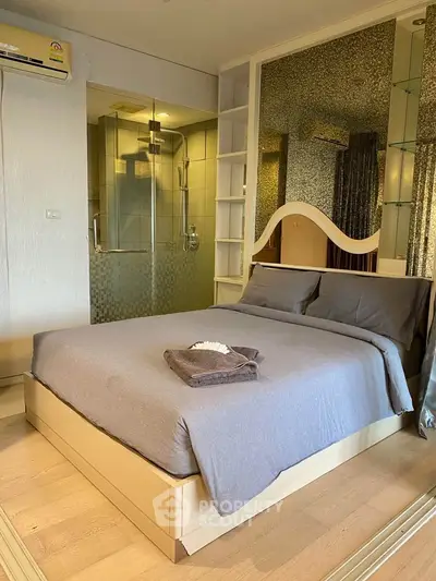 Modern bedroom with ensuite bathroom featuring glass shower and elegant decor.