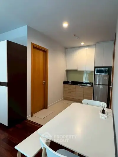 Modern kitchen with sleek cabinets and dining area in cozy apartment