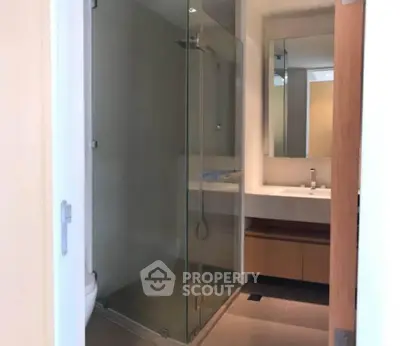 Modern bathroom with glass shower and sleek vanity in contemporary apartment.