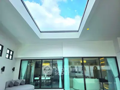Luxurious living room with skylight and modern decor, featuring spacious seating and elegant dining area.